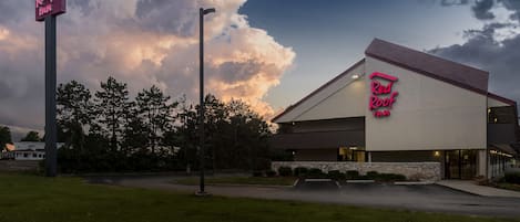 A Red Roof Inn with a prominent neon sign, a modern building design, and a parking lot.