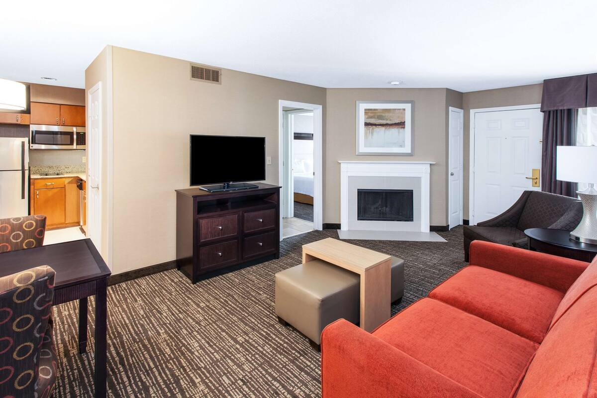 A hotel room with a living area, kitchenette, and a fireplace.