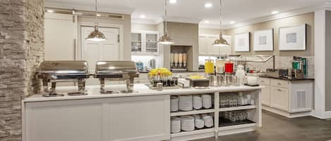A modern kitchen with a central island, pendant lighting, and a stone accent wall.