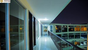 A corridor with glass doors, a railing, and a view of a building with multiple floors. - Ambassador (Mérida)