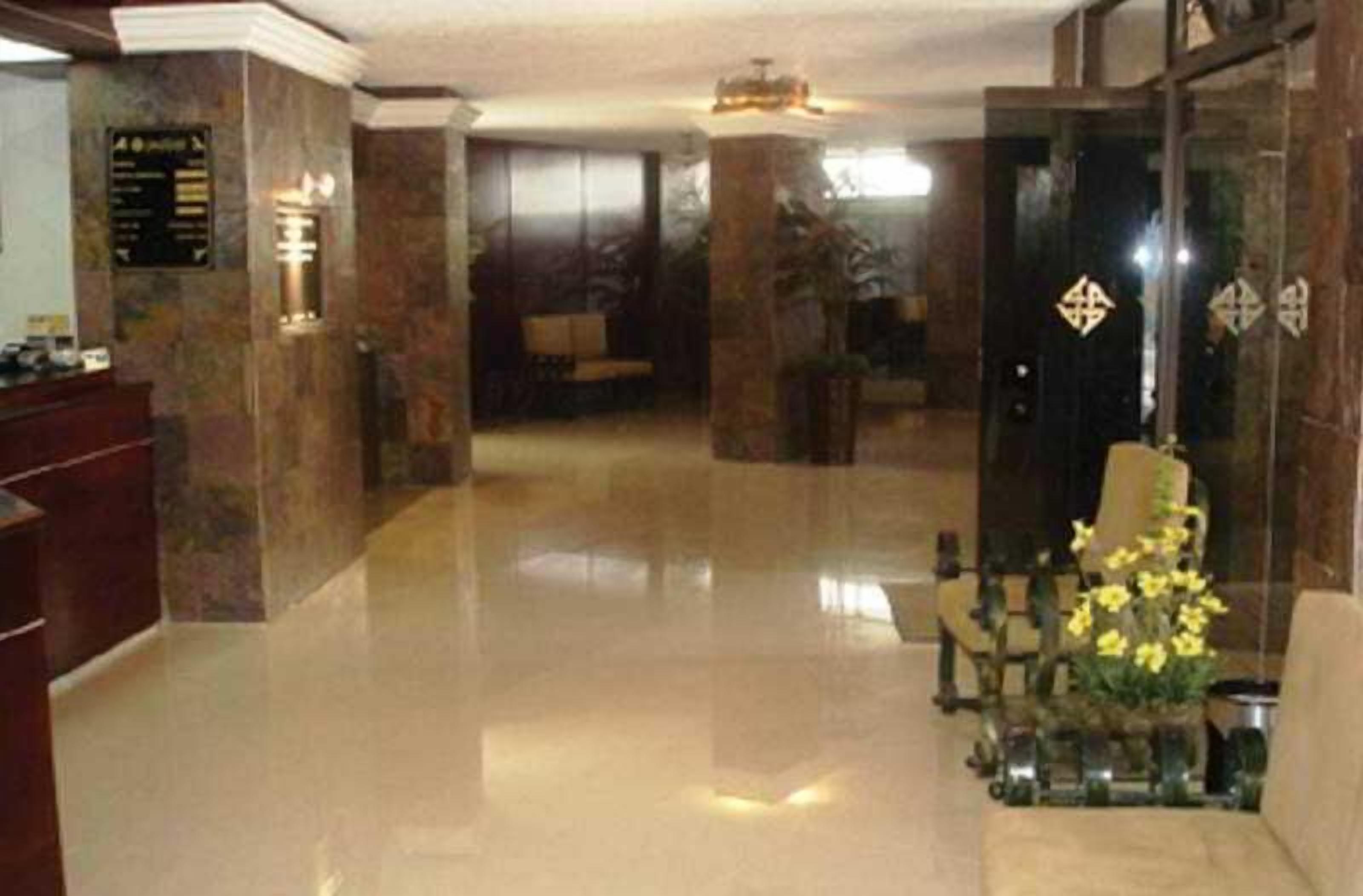 A lobby with a reception desk, a seating area, and a reception desk with a flower arrangement.