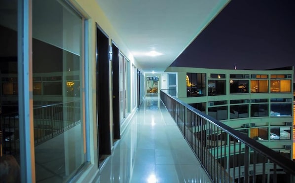 A corridor with glass doors and windows, leading to a balcony with a view of other buildings. - Ambassador (Mérida)