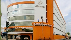 A modern hotel with a curved facade, multiple floors, and a prominent orange and white color scheme. - Ambassador (Mérida)