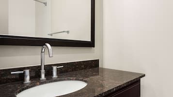 A bathroom with a white sink, dark granite countertop, and a large mirror.