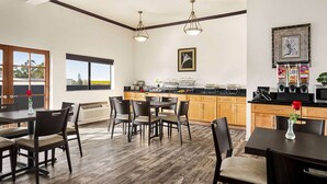 Una cocina moderna con armarios de madera, un comedor con sillas oscuras y un amplio ventanal que ofrece vistas al exterior.
