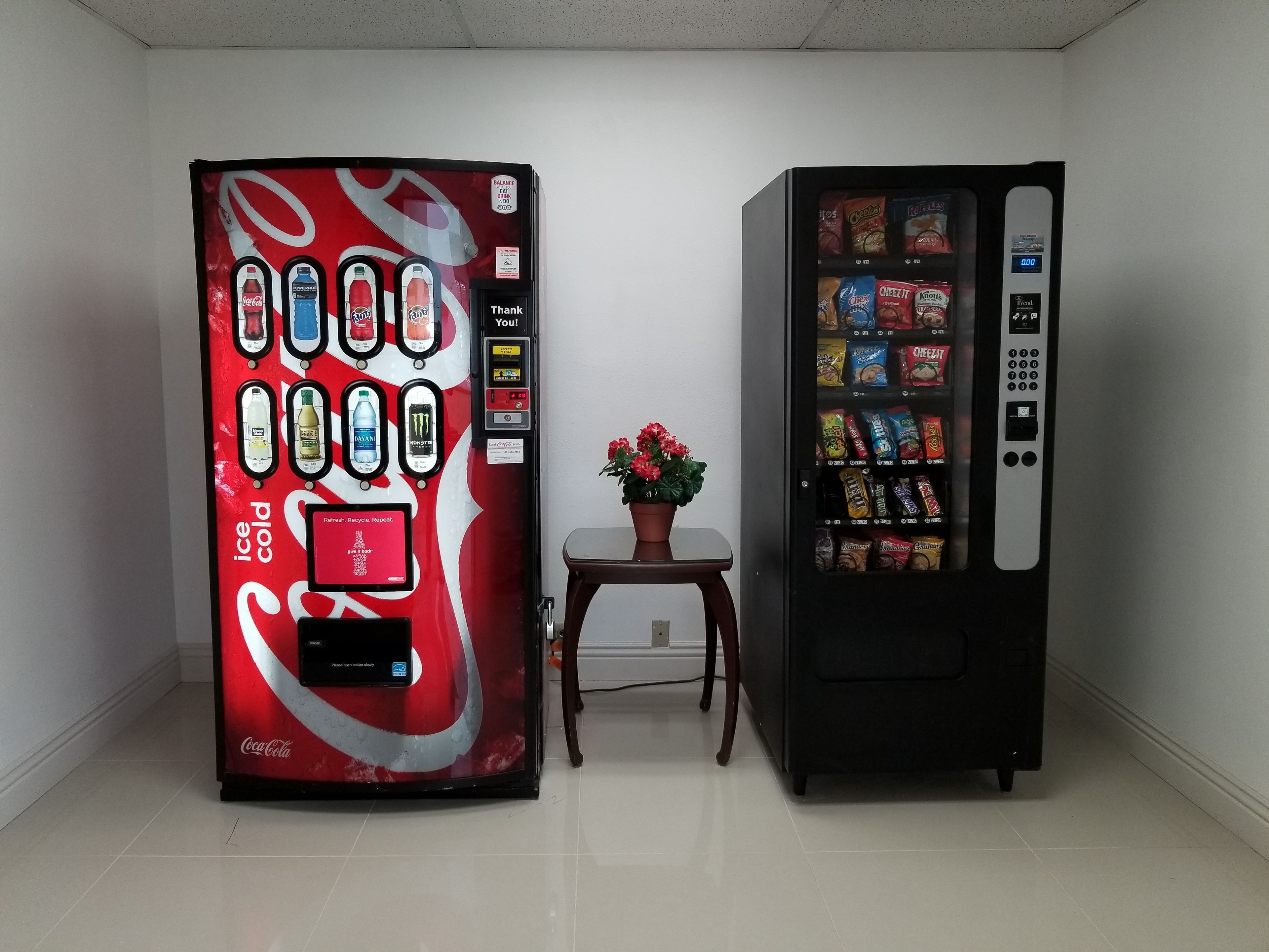 Zwei Getränkeautomaten, einer mit Coca-Cola-Branding und der andere mit verschiedenen Snacks.