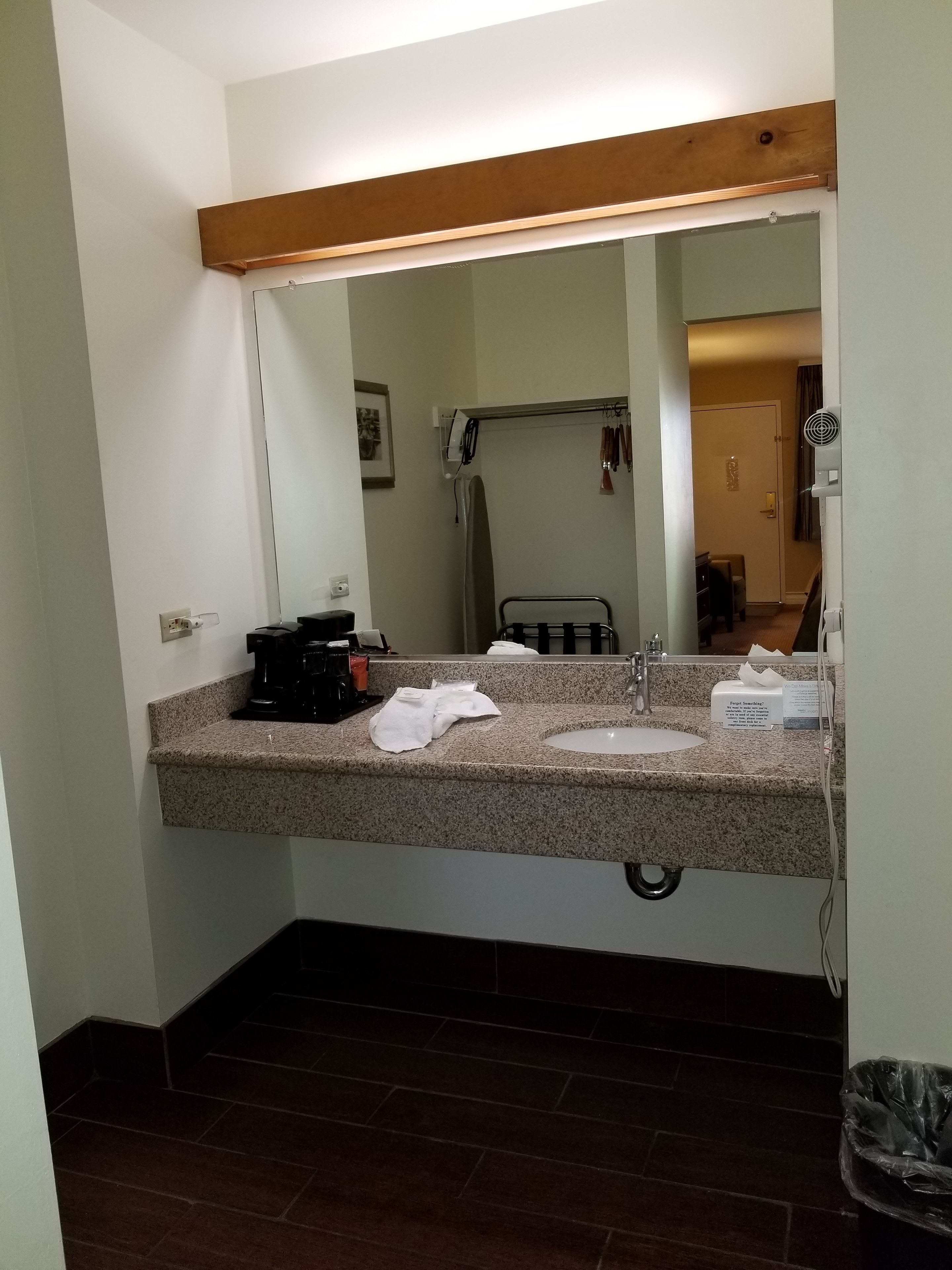 A bathroom with a granite countertop, a sink, a mirror, and a towel rack.