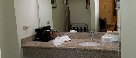 A bathroom with a granite countertop, a sink, a mirror, and a towel rack.