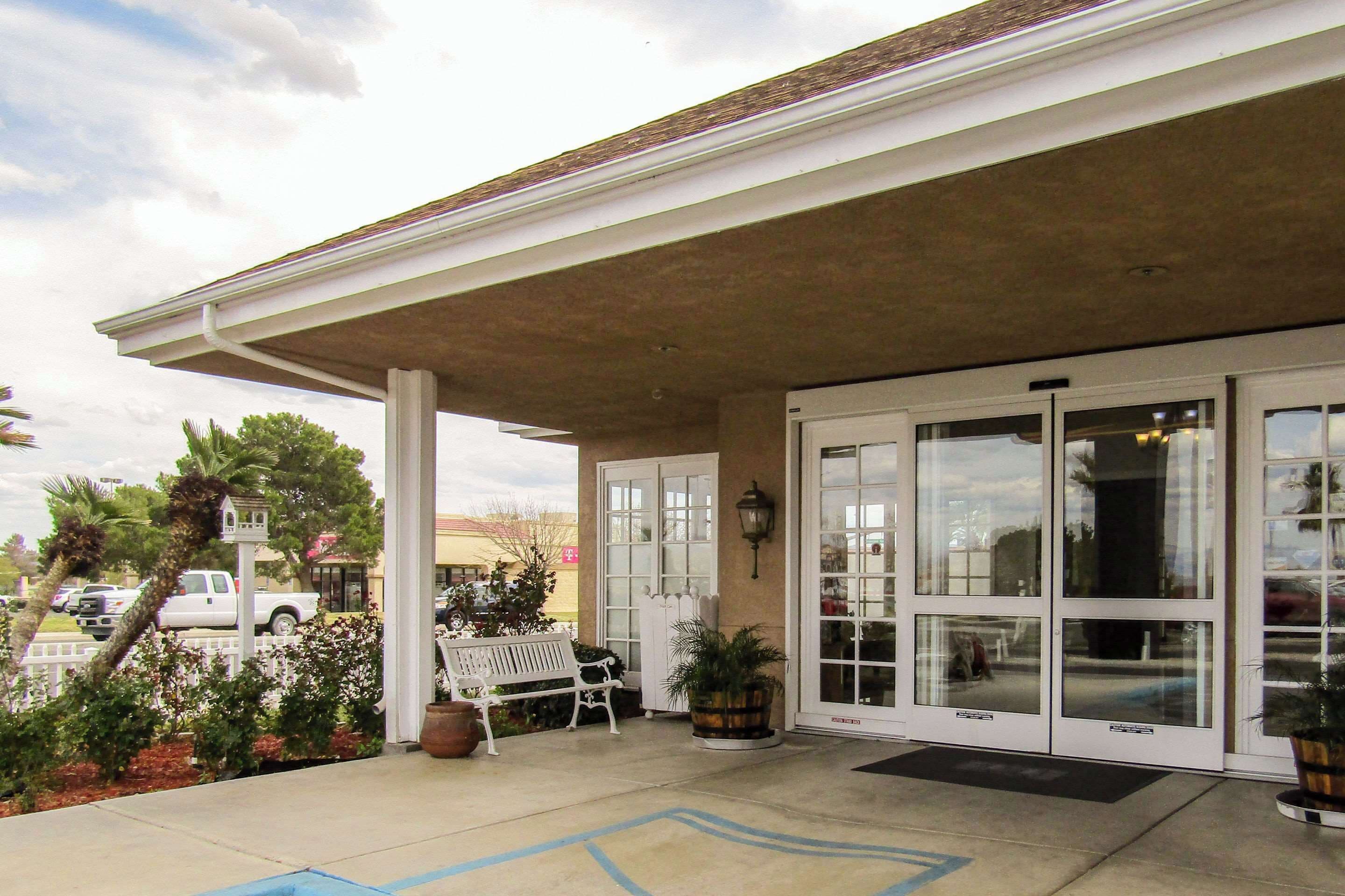A covered outdoor area with a bench, potted plants, and a white pickup truck parked nearby.