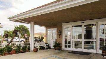 A covered outdoor area with a bench, potted plants, and a white pickup truck parked nearby.