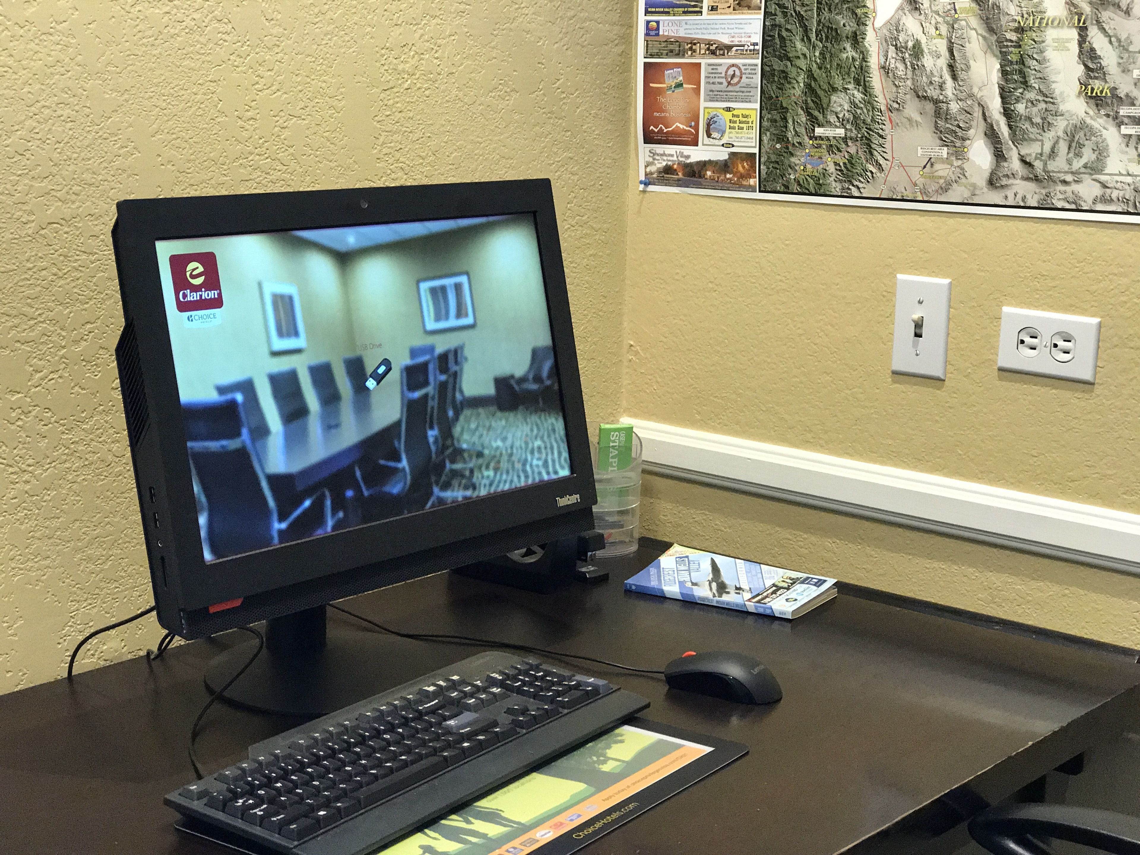 A conference room with a large screen, a keyboard, and a mouse on a desk.