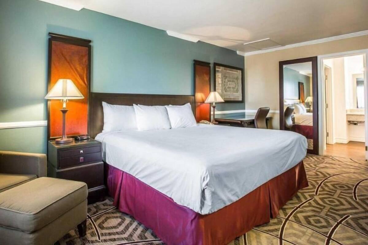 A hotel room with a large bed, bedside tables, a desk, and a chair.