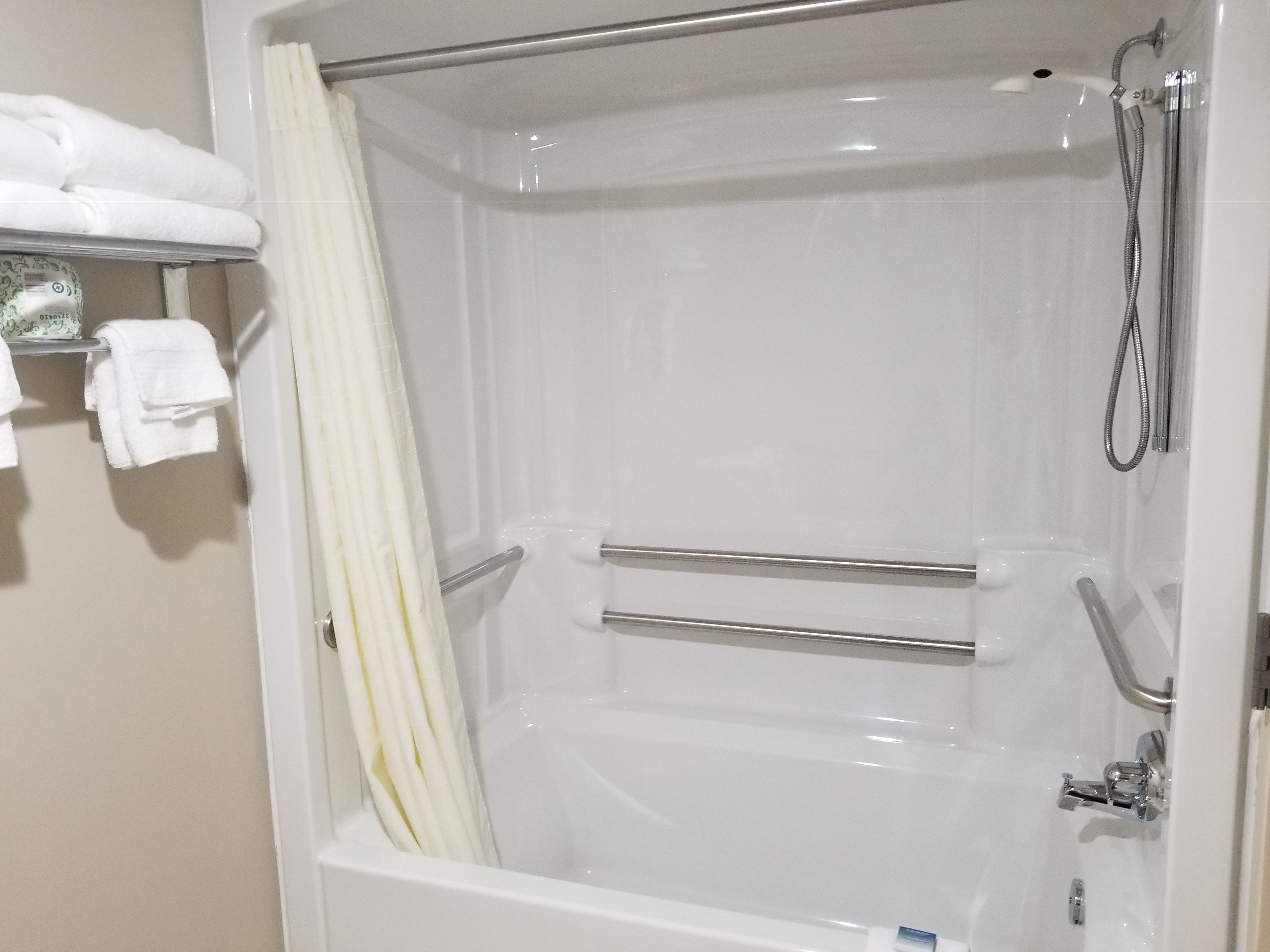 A white bathtub with a showerhead and grab bars.