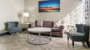 A modern living room with a round coffee table, two armchairs, a sofa, and a lamp. - Best Western Beacon Inn (Grand Haven)