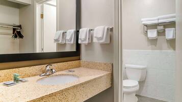 A bathroom with a granite countertop sink, a mirror, and a toilet.