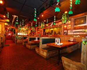A restaurant with booths, a bar area, and a television screen. - Quality Inn Downtown Stuart (Stuart)