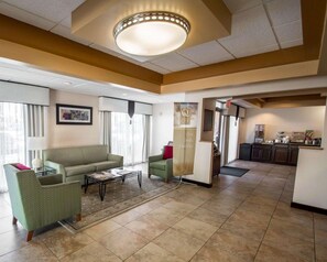 A hotel lobby with a sofa, armchairs, a coffee station, and a view of the kitchen. - Quality Inn Downtown Stuart (Stuart)