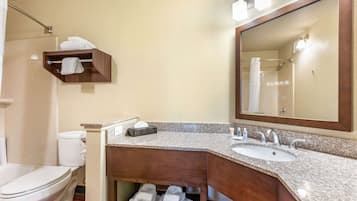 Un baño con lavamanos, espejo, toallero y retrete.