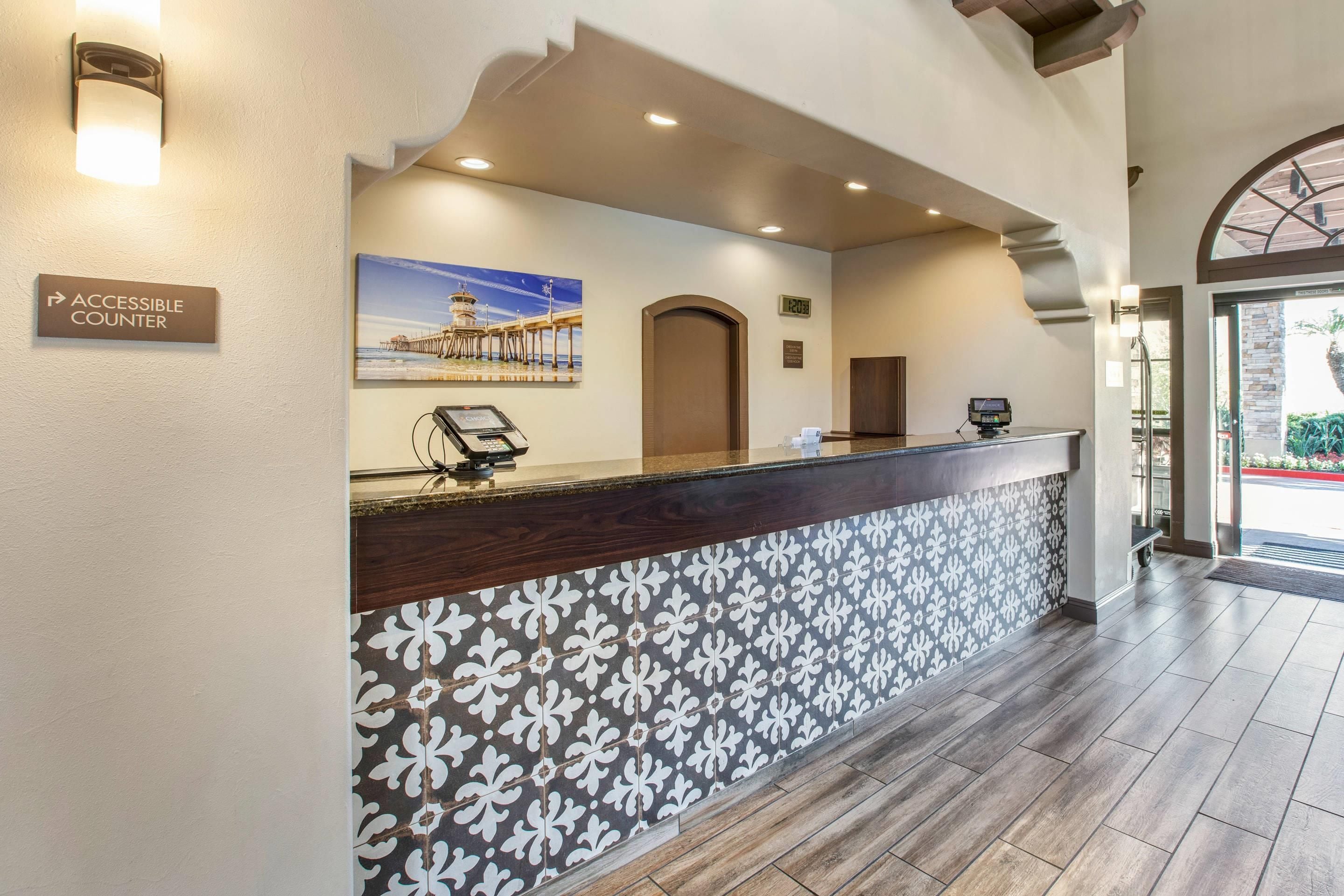 A reception desk with a digital display, a clock, and a sign for an accessible counter.