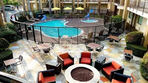 A rooftop pool area with lounge chairs and a fire pit, surrounded by a fence and overlooking a multi-story building. - Comfort Inn & Suites Orange County John Wayne Airport (Santa Ana)