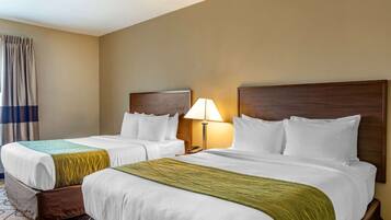 A hotel room with two beds, a nightstand with a lamp, and a curtain on the window.