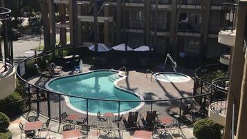 A hotel pool area with a circular pool, lounge chairs, and umbrellas.