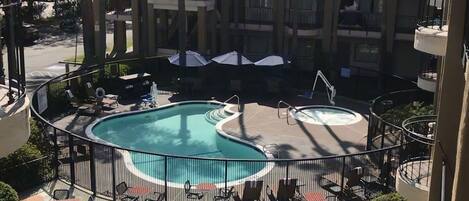 A hotel pool area with a circular pool, lounge chairs, and umbrellas.