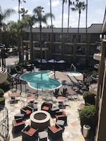 A hotel pool area with a circular pool, lounge chairs, and umbrellas.