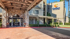 A Comfort Inn & Suites with a stone facade, large windows, and a covered entrance area. - Comfort Inn & Suites Orange County John Wayne Airport (Santa Ana)