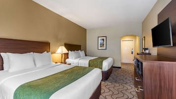 A hotel room with two beds, a TV, a desk, and a door leading to a hallway.