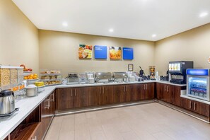Ein Bereich für das Frühstück mit Selbstbedienung, der verschiedene Speisen, eine Kaffeemaschine und einen Kühlschrank bietet.