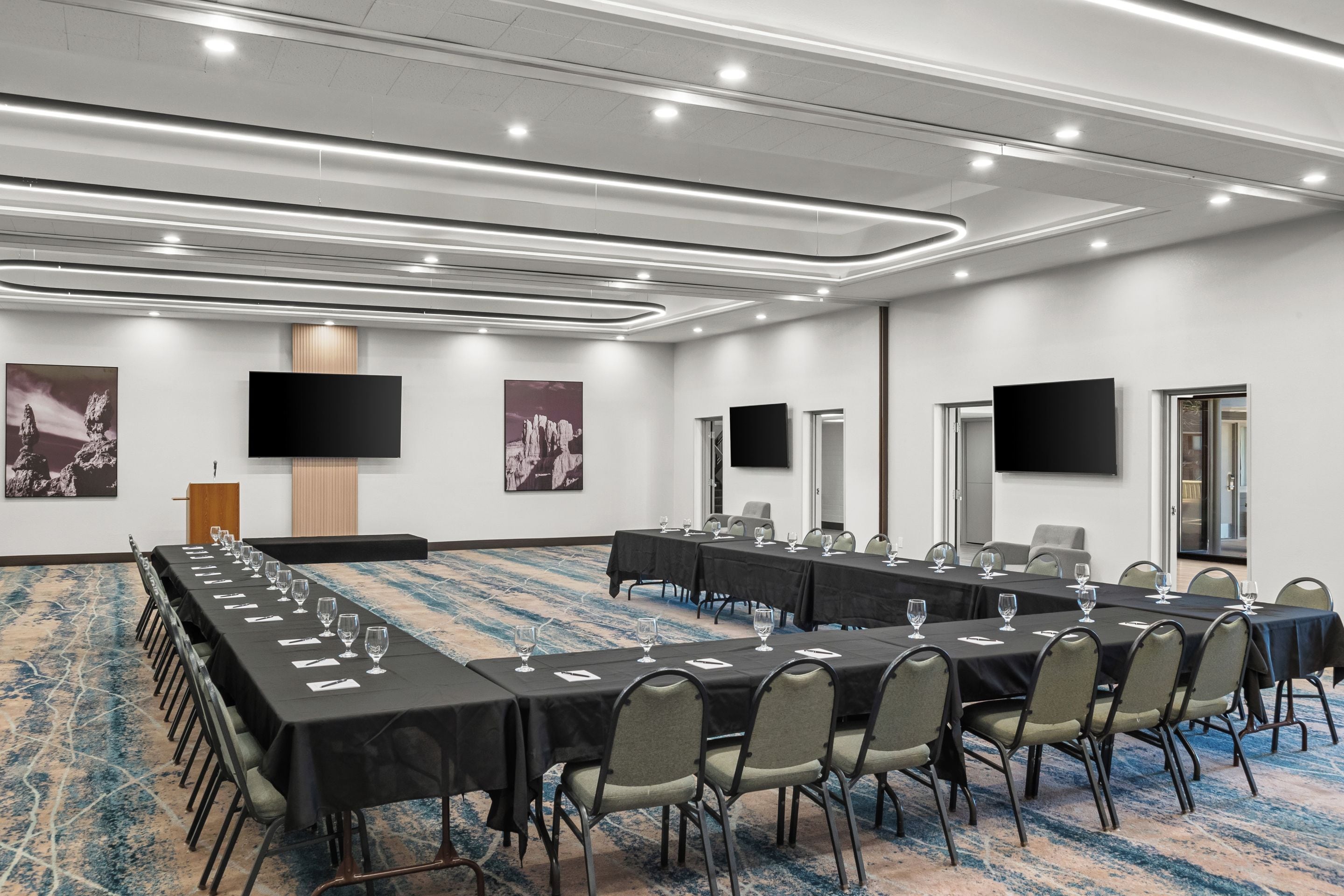 A conference room with long tables, chairs, and a carpeted floor.