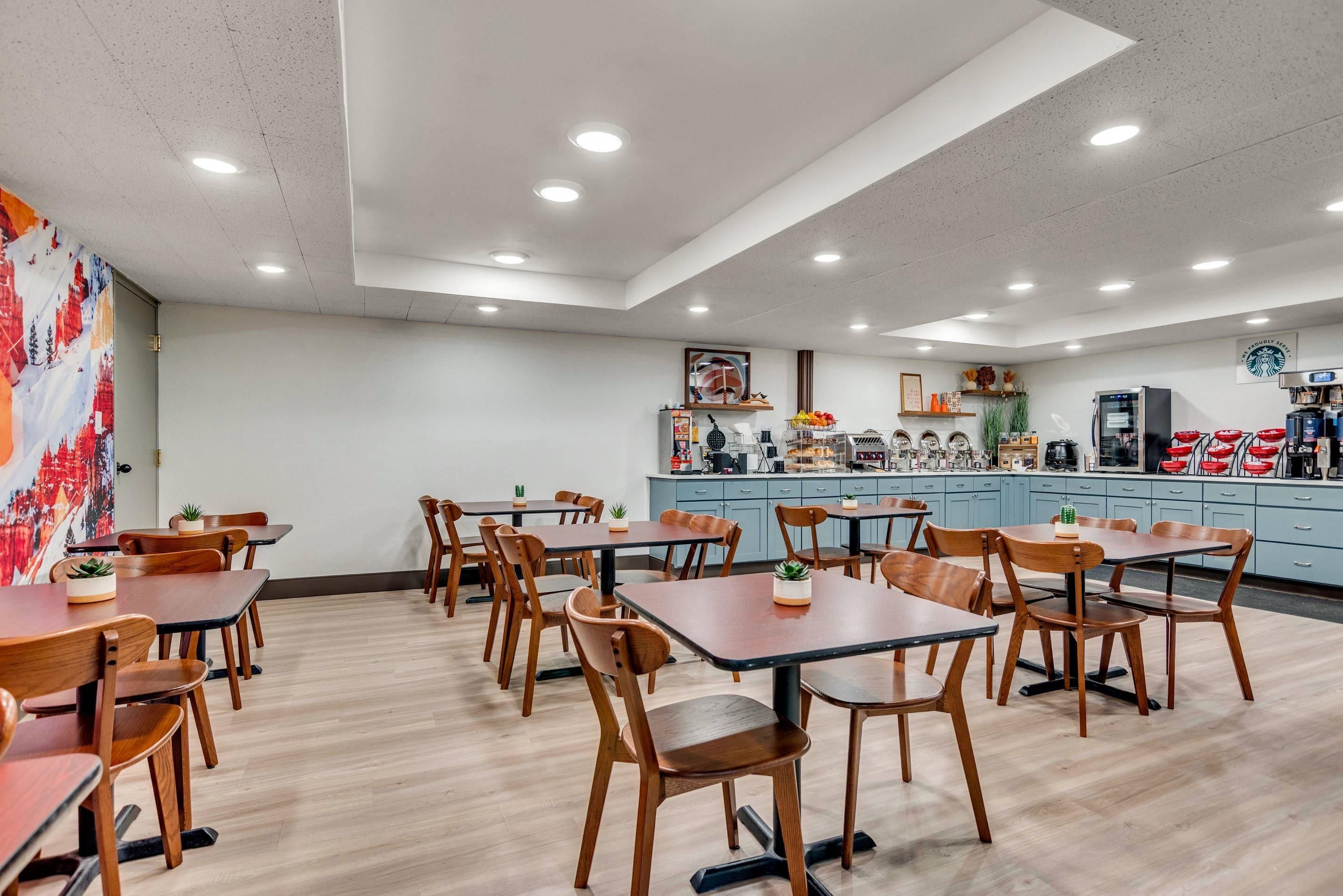 Un restaurante con mesas y sillas de madera, una zona de cocina y el logotipo de Starbucks en la pared.