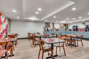Un restaurant avec des tables et des chaises en bois, un espace cuisine et le logo de Starbucks sur le mur.