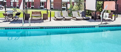 Een seizoensgebonden buitenzwembad en ligstoelen