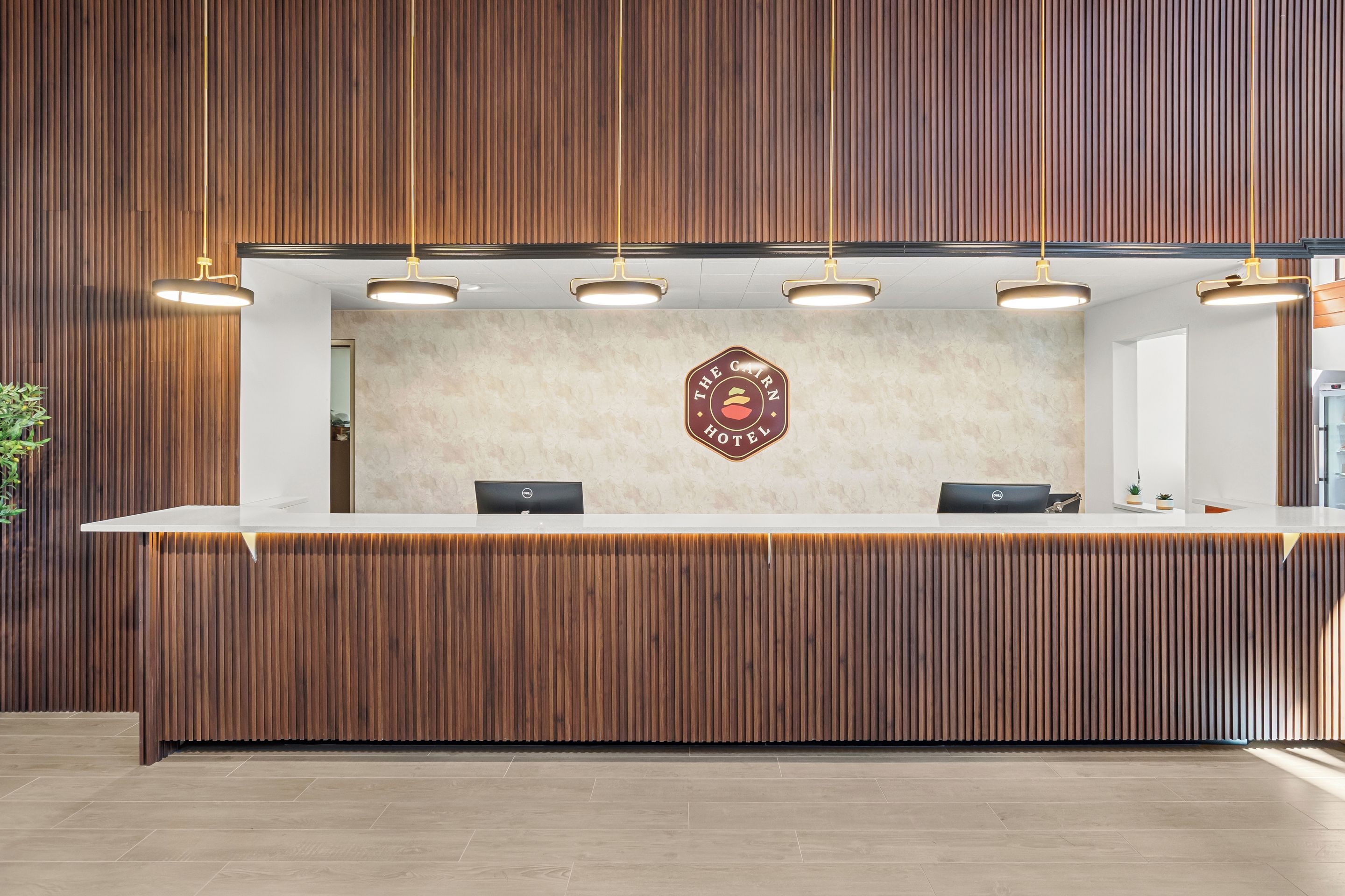 A reception desk with a wooden panel backdrop, a logo on the wall, and overhead lighting.