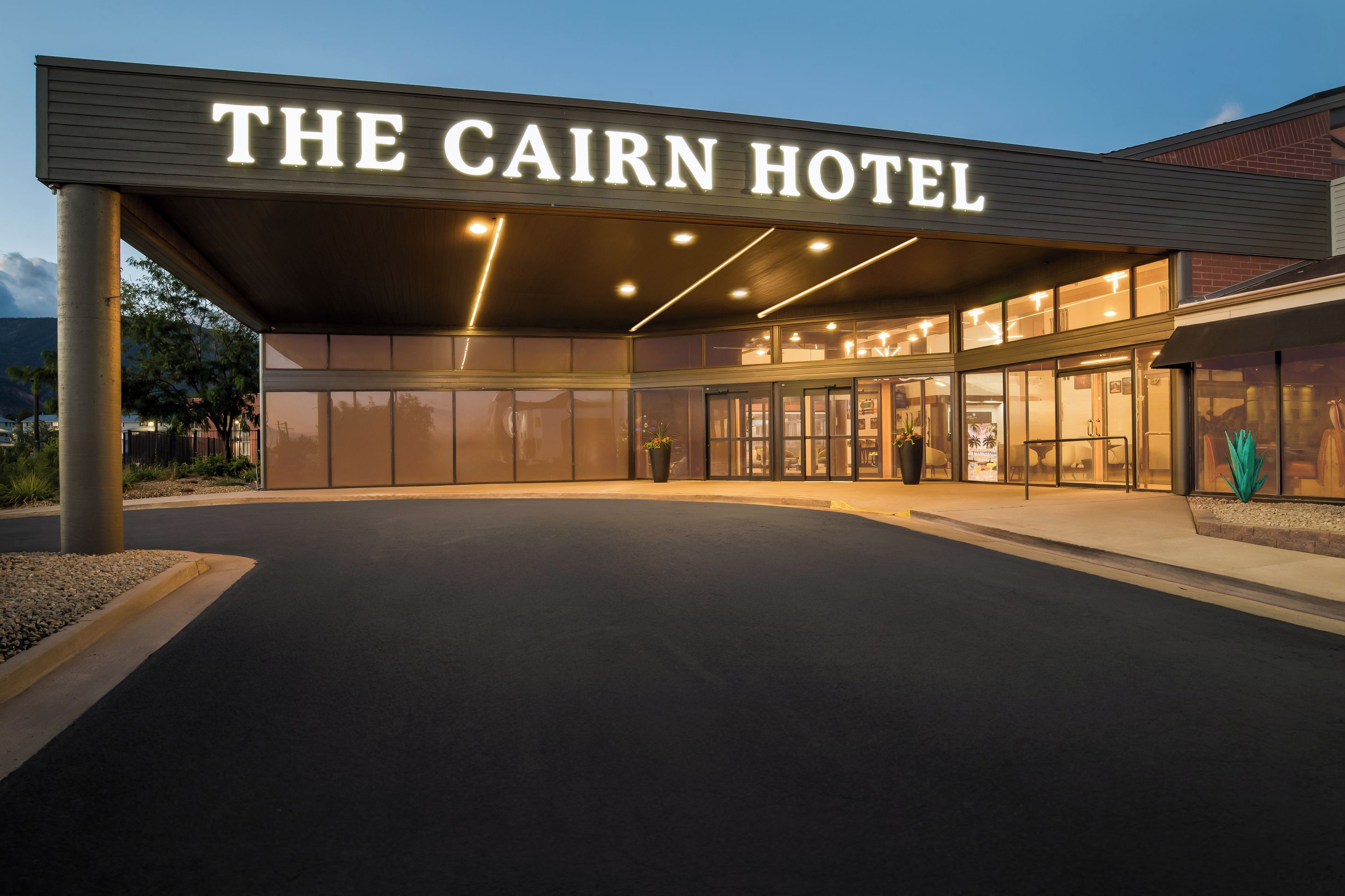 The exterior of The Cairn Hotel with a covered entrance and a clear view of the lobby area.