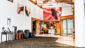 A spacious lobby with a high ceiling, a reception desk, leather seating, and large wall art. - The Cairn Hotel, an Ascend Collection Hotel (Cedar City)