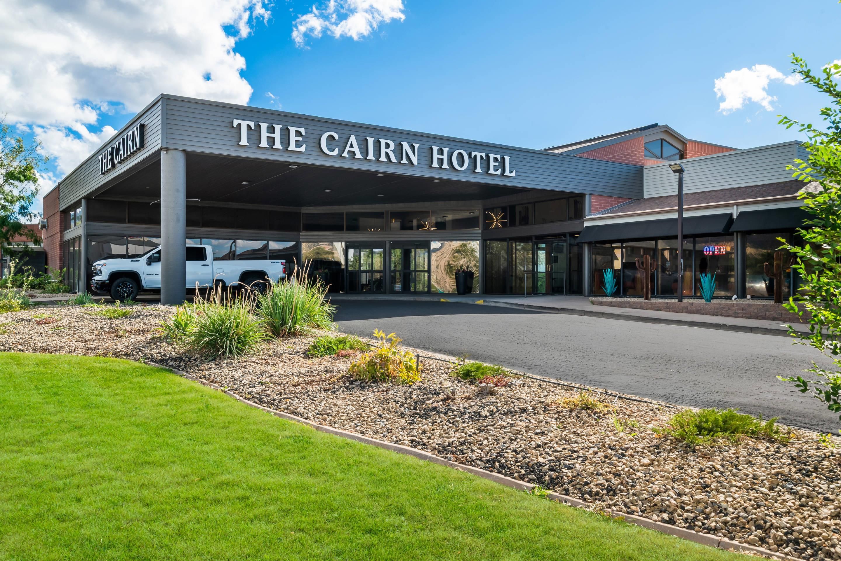 Hotel Cairn met een overdekte ingang, een parkeerplaats en een aangelegde tuin.