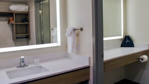 Une salle de bain avec un lavabo blanc, un miroir, un porte-serviettes et une étagère en bois.
