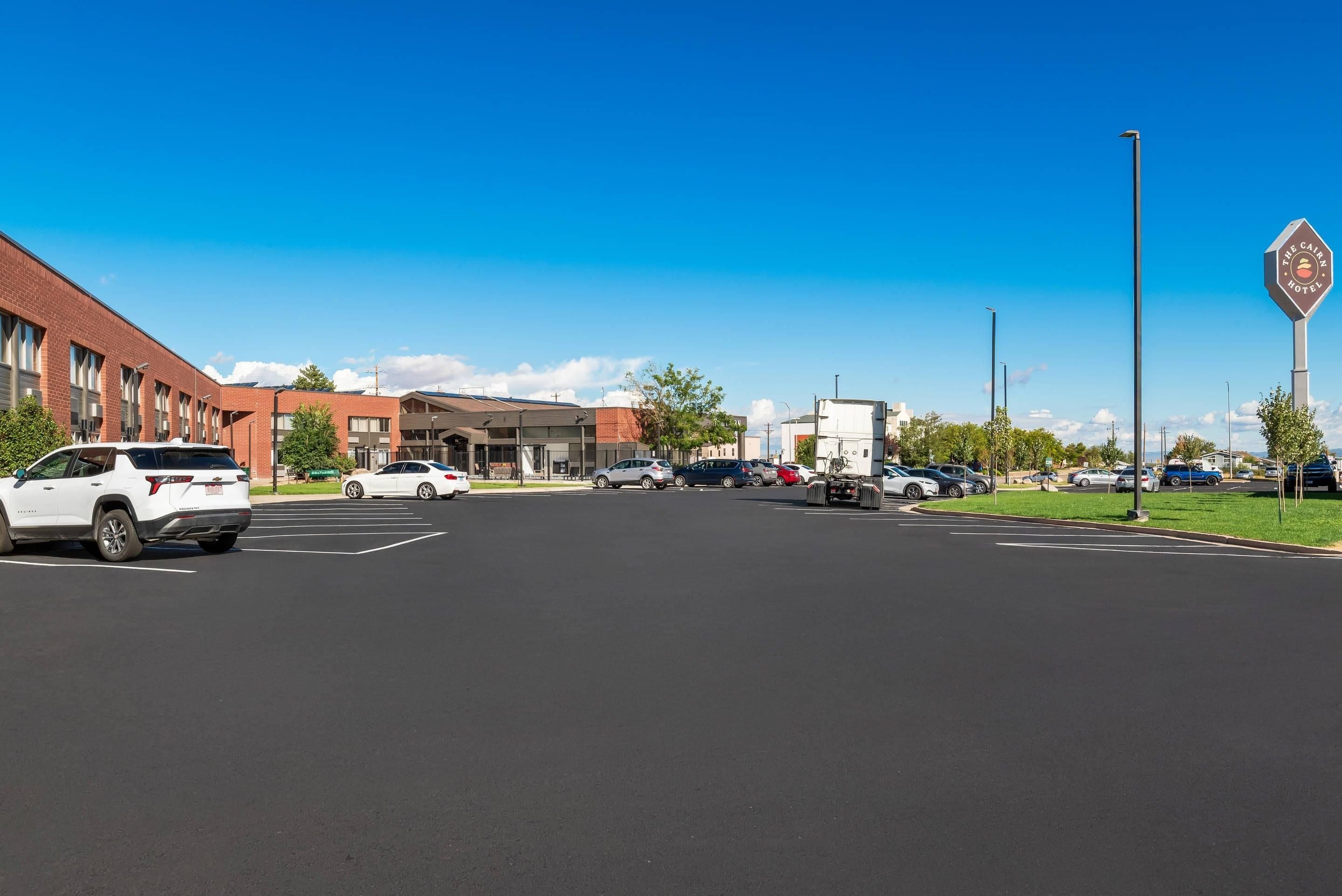 A parking lot with multiple cars, a building with a red brick facade, and a sign for 'The Carn Hotel' in the background.