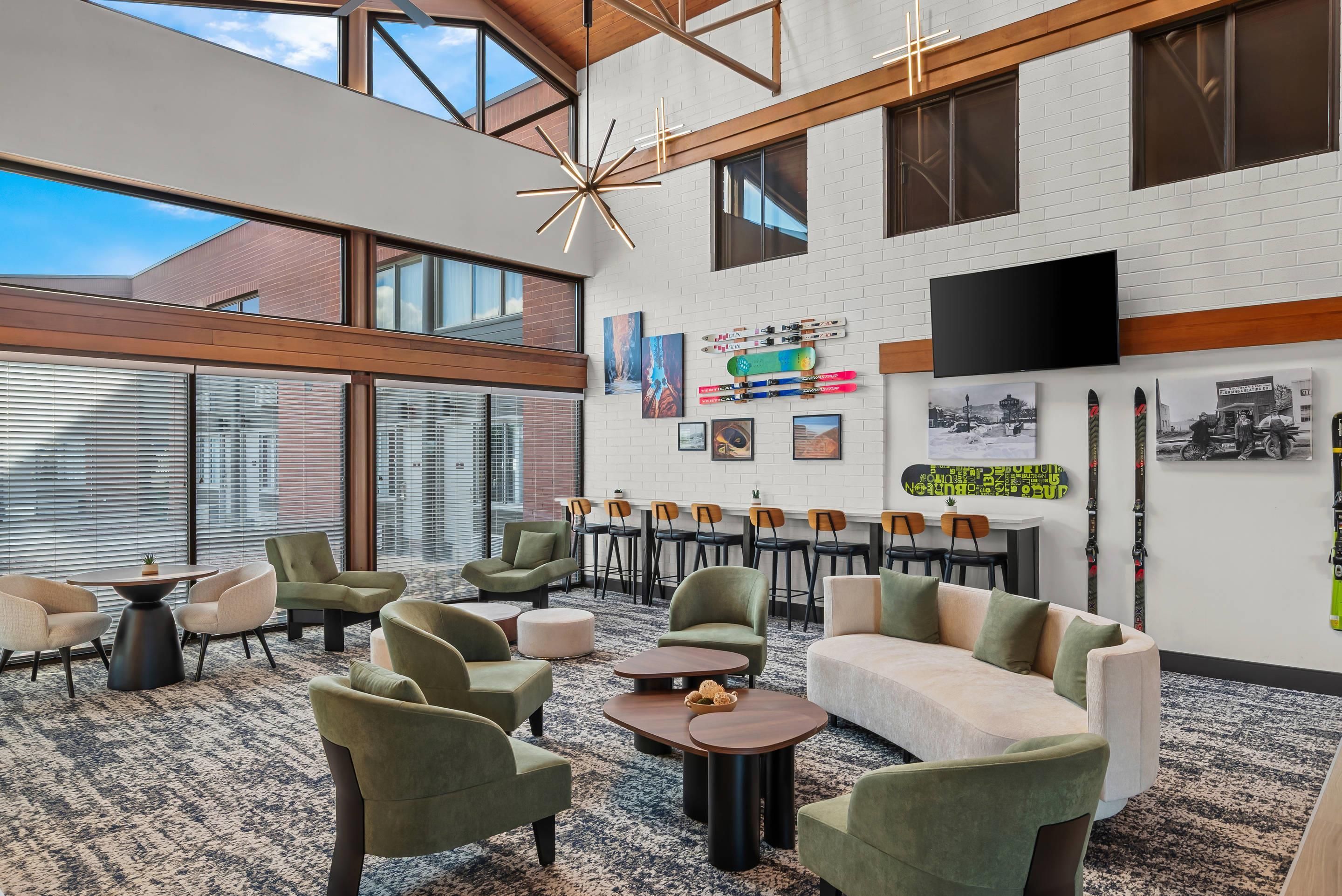 A spacious indoor area with high ceilings, large windows, and a variety of seating arrangements including sofas and chairs.