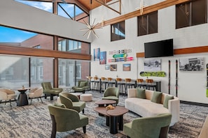 A spacious indoor area with high ceilings, large windows, and a variety of seating arrangements including sofas and chairs. - The Cairn Hotel, an Ascend Collection Hotel (Cedar City)