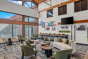 A spacious indoor area with high ceilings, large windows, and a variety of seating arrangements including sofas and chairs.