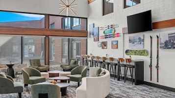 A modern lounge area with seating, a mounted TV, and ski equipment on the wall.