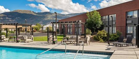 A pool area with lounge chairs and a view of mountains.