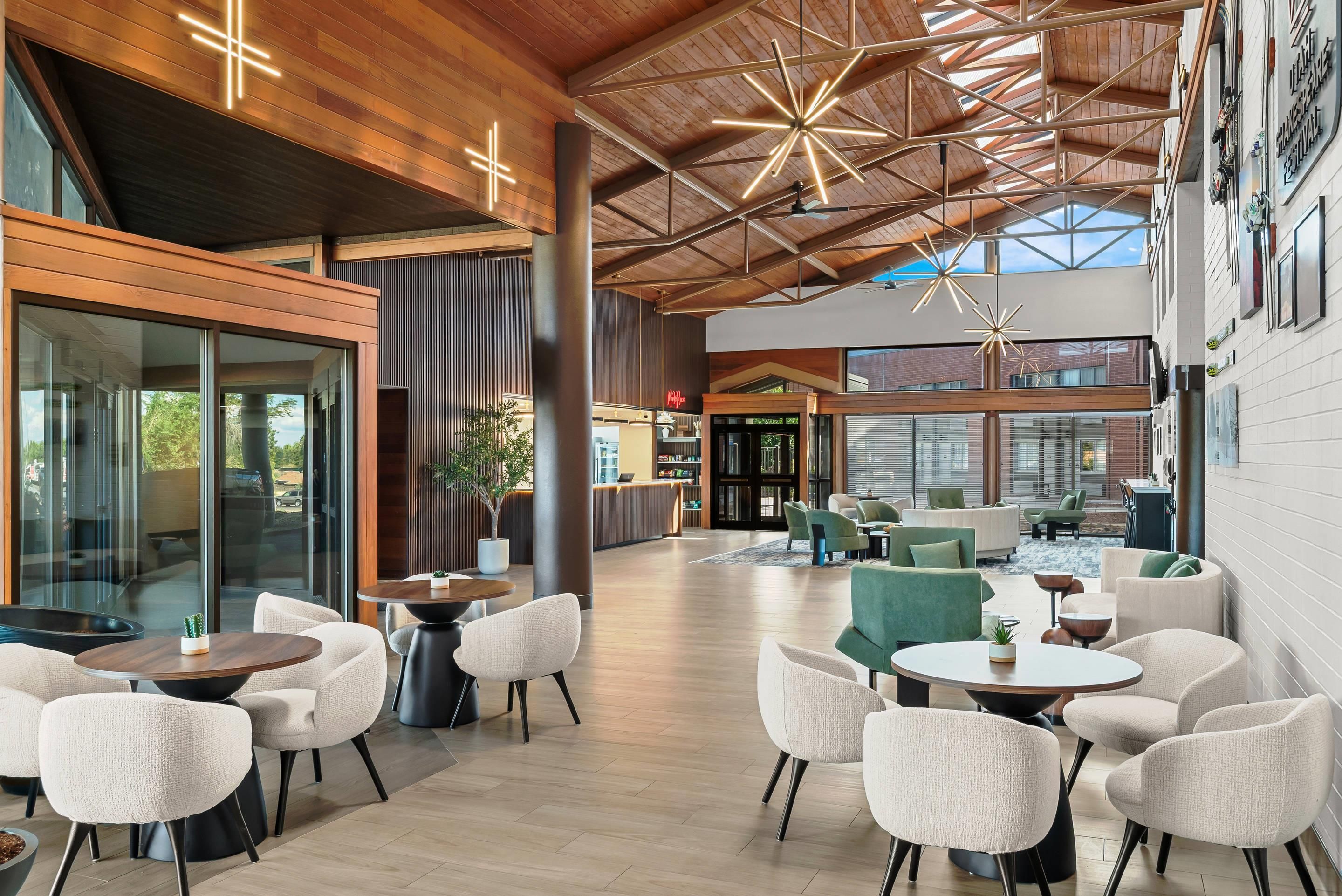 A spacious indoor area with a high ceiling, modern furniture, and large windows allowing natural light.