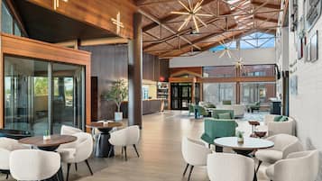 A spacious indoor area with a high ceiling, modern furniture, and large windows allowing natural light.