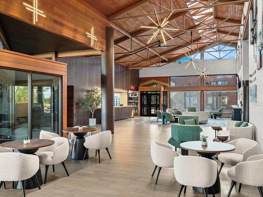 A spacious indoor area with a high ceiling, modern furniture, and large windows allowing natural light.