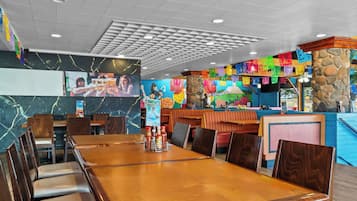 Un restaurante con una larga mesa de madera, cabinas y un pilar de piedra.
